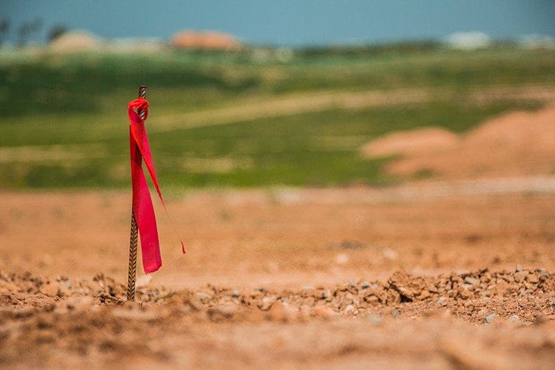 Metal survey peg with red flag on construction site